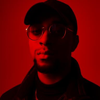 photo of man wearing black cap against red backdrop